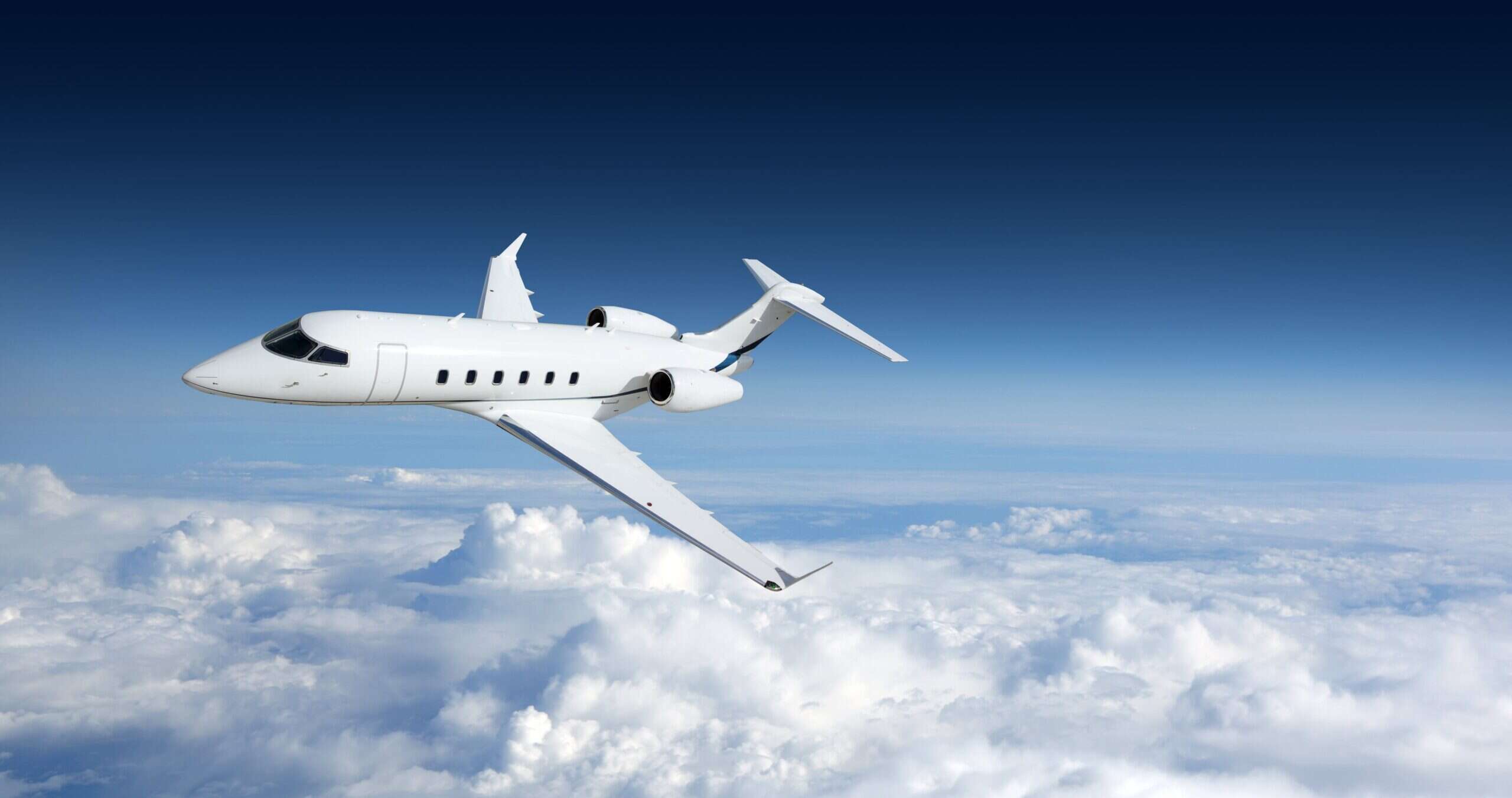 white private jet flying in clouds