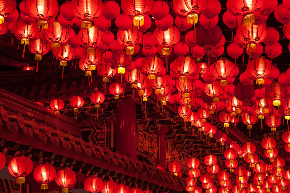 100's of red lanterns hang on strings around a temple
