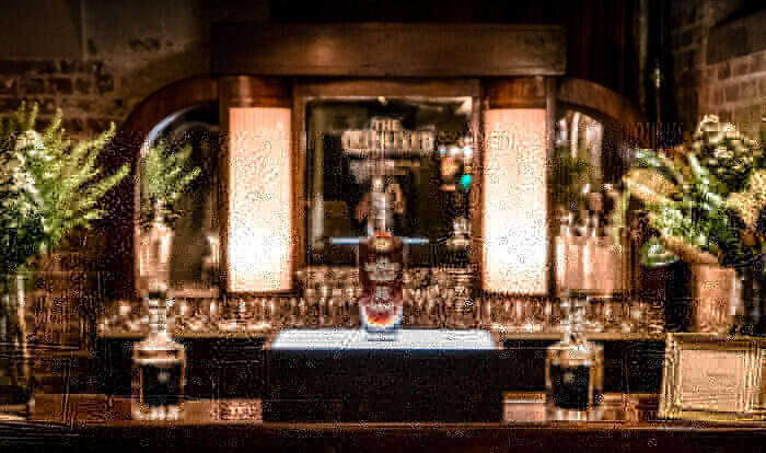 Bottle of Glenlivet Scotch stands on bar between two whisky decanters