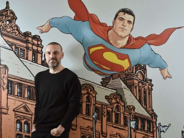 Frank Quitely Picture infront of artwork of Kelvinhall museum with Superman