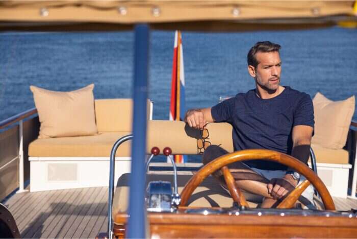 man driving yacht wearing feadship ocean collection tshirt