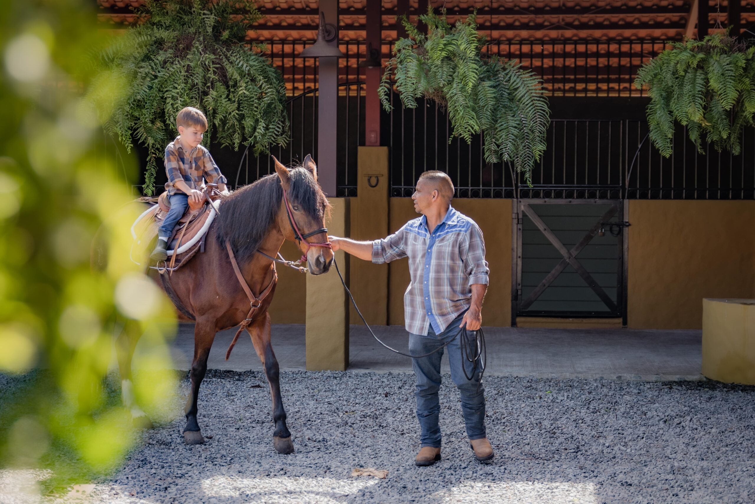 man teaching child to horseride in auberge enriching lives program