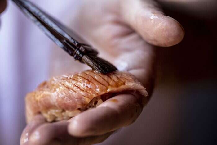 sushi fish being painted with marinade