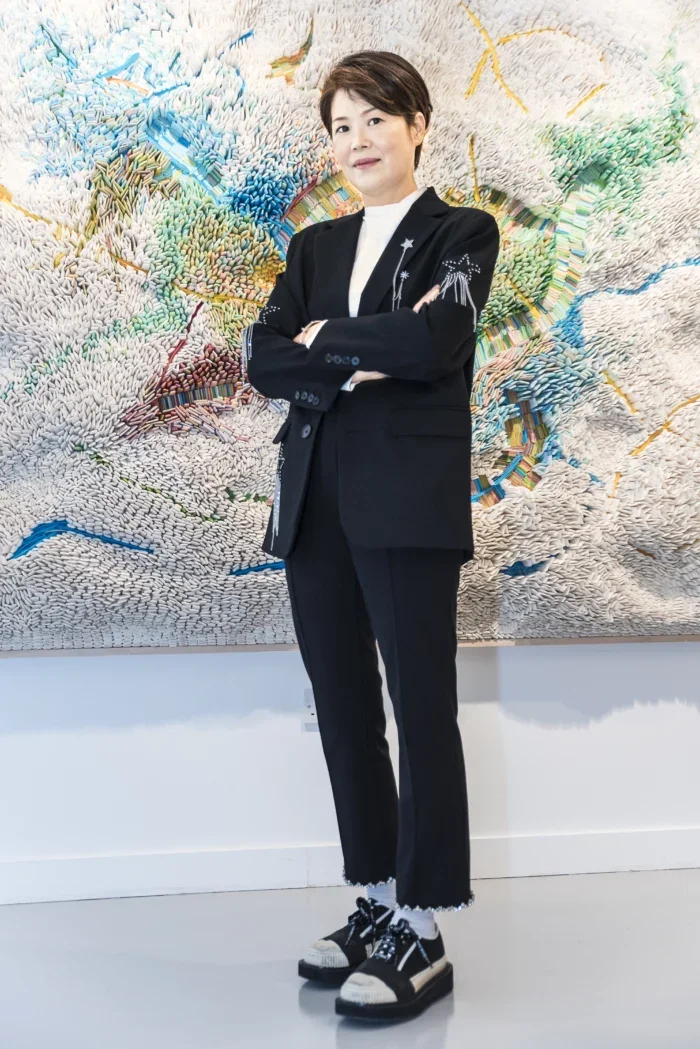 Artist Ilhwa Kim standing with her work
