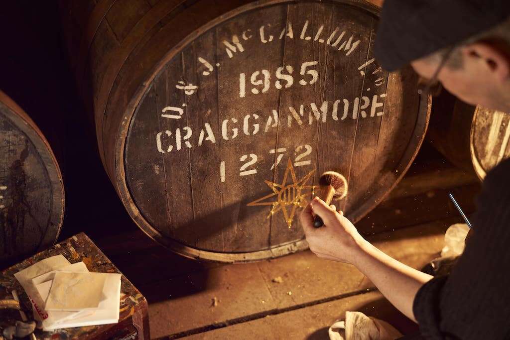 person touching whisky cask