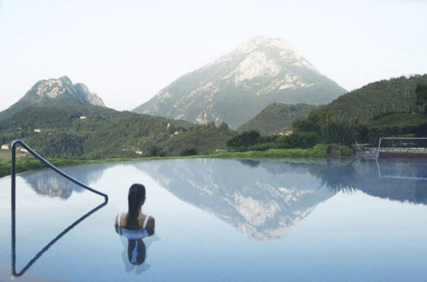 A woman is looking at the mountain view from the pool at the Lefay Resort.