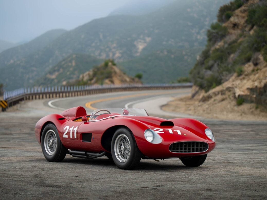 Image showing the 1957 Ferrari 625 TRC Spider against a mountain backdrop on the road.