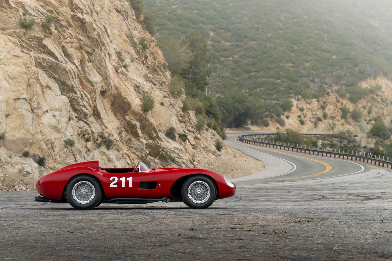 The 1957 Ferrari 625 TRC Spider pictured against cliffs on a mountain road.